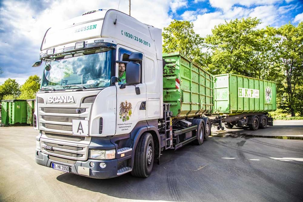 Weißer Lkw mit mit grünen Abfallcontainern der Firma Holzkontor Preussen GmbH